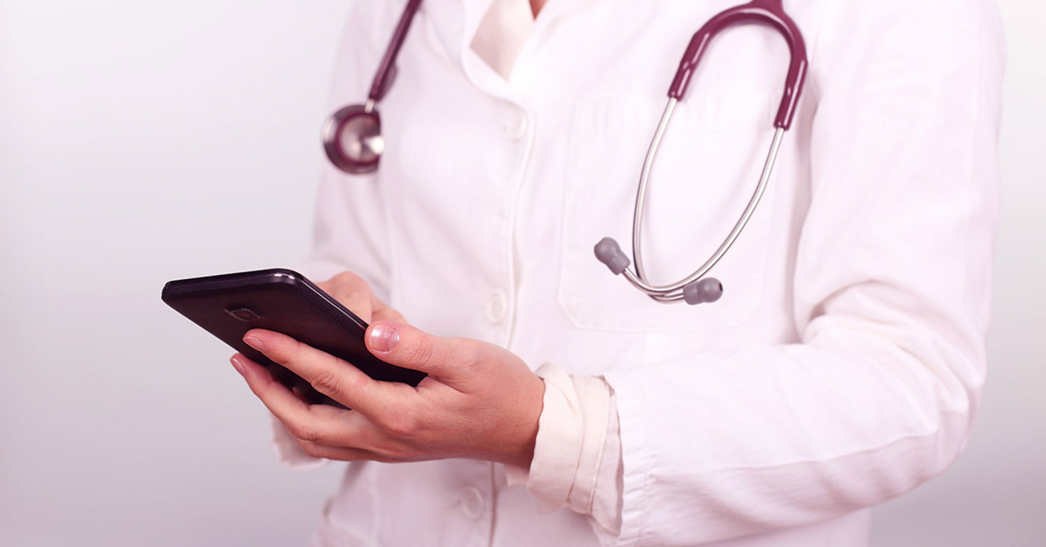 Vårdpersonal med stetoskop kollar i telefonen