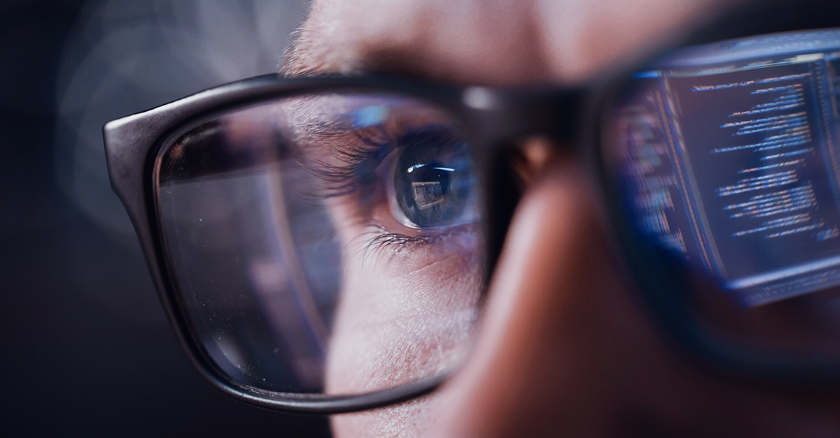 Närbild på person med glasögon, där man i glasögonen ser en reflektion från en datorskärm.