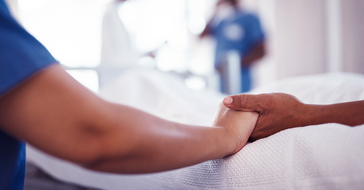 Två personer håller hand i sjukhusmiljö