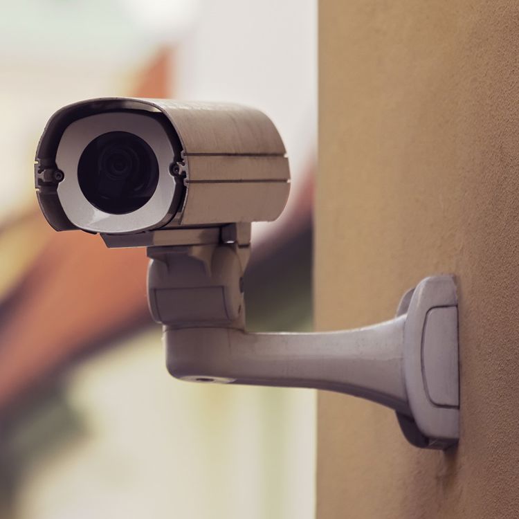 En kamera som är monterad på en gul fasad till ett lägenhetshus.