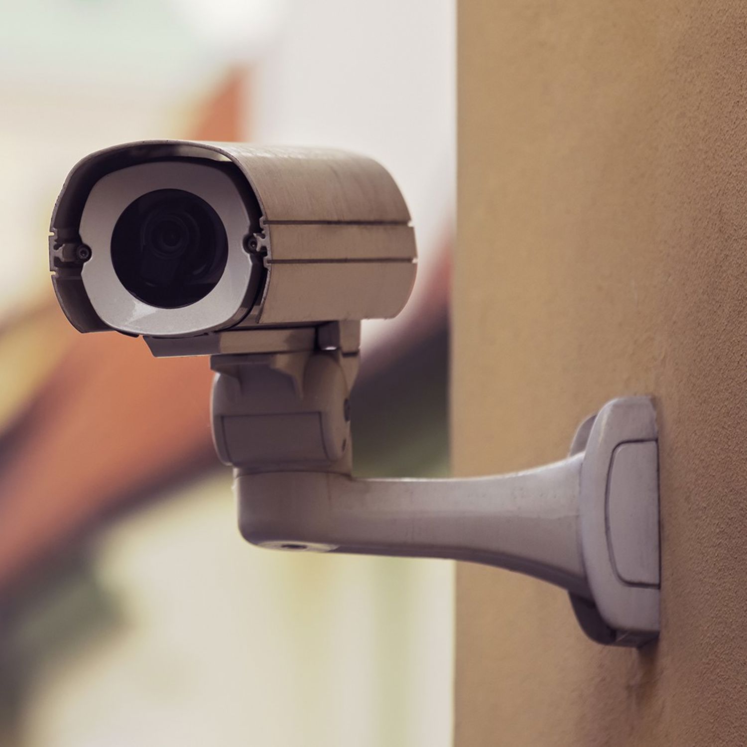 En kamera som är monterad på en gul fasad till ett lägenhetshus.