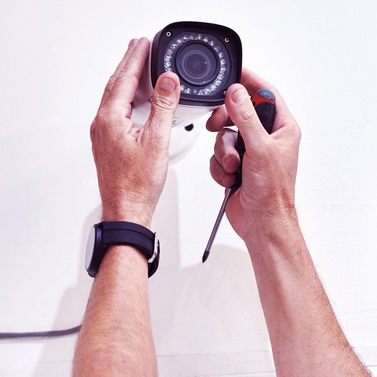 En man monterar en kamera på en vägg.