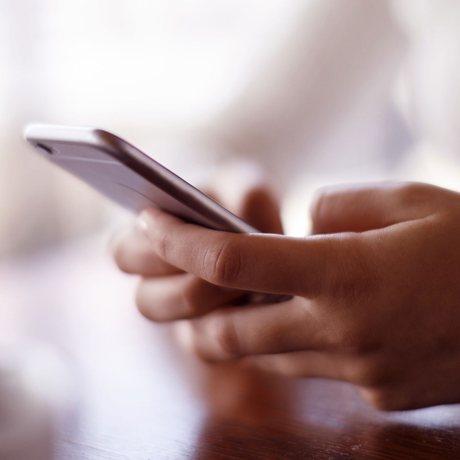 Närbild på händer som scrollar på mobil.